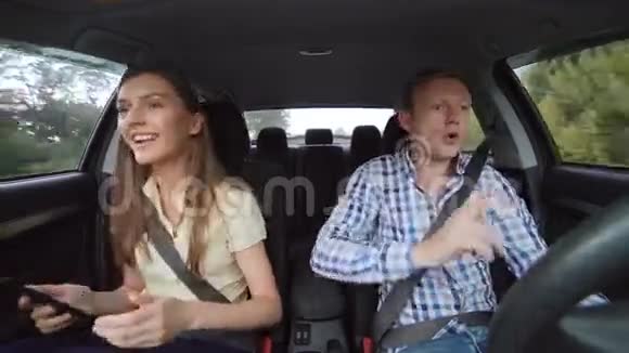 年轻夫妇坐在车里跳舞微笑着用平板电脑4K视频的预览图