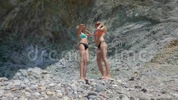 两个穿比基尼的模特在岩石的背景下跳舞视频的预览图