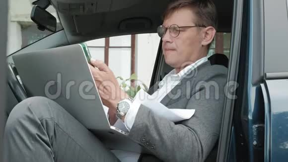成熟的商人在车里打电话视频的预览图