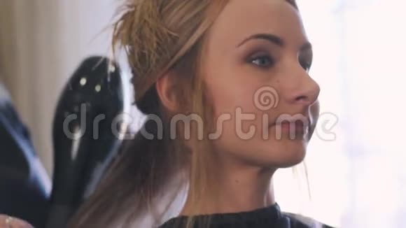 一个年轻的金发女人在豪华美容院做完她的发型有着长长卷发的女士视频的预览图