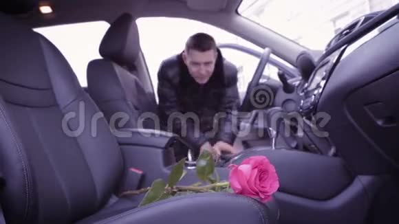 男人从车里拿起一朵粉红色的玫瑰视频的预览图