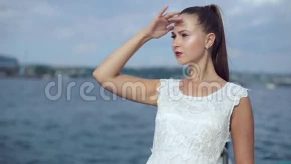 漂亮的年轻女子扎着马尾辫穿着一件浅白色的裙子站在船上摆姿势视频的预览图