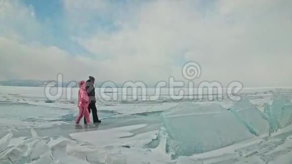 在冰封的湖面上年轻夫妇在冬天散步时玩得很开心恋人们在冰上行走彼此拥抱视频的预览图
