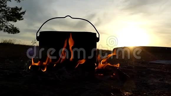 夕阳西下一个盛着水的大锅在篝火里视频的预览图