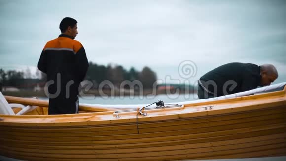 师傅和他的助手在河上的木帆船上工作视频的预览图