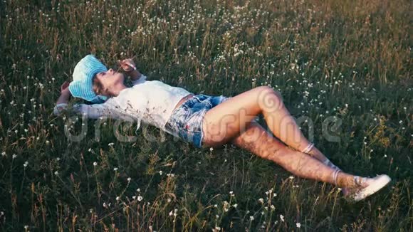 美丽的微笑女孩躺在春田上草甸充满欢笑和快乐的年轻女模特的健康画像视频的预览图