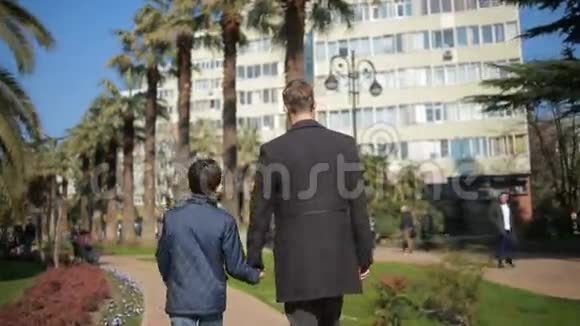 父子俩正沿着城市的小巷在公园里散步视频的预览图