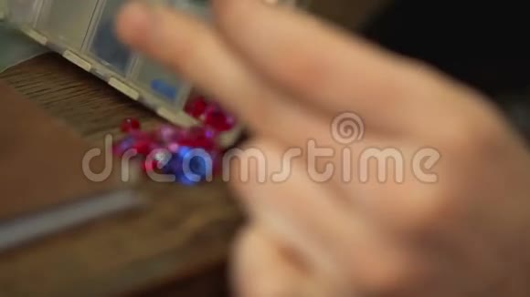 艺术家把塑料盒子里的宝石倒进木桌上视频的预览图