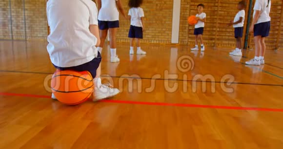 4k学校篮球场上坐篮球的女学生视频的预览图