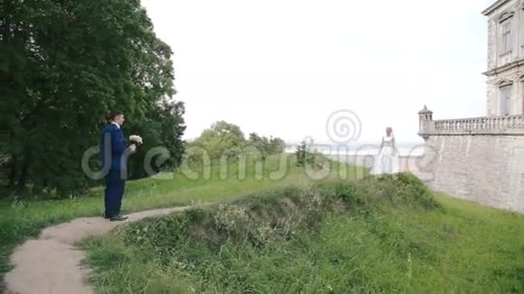 新郎带着一束结婚花来到城堡附近的新娘面前视频的预览图