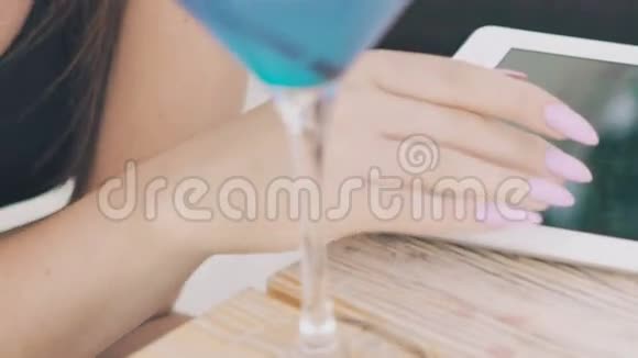 把蓝色鸡尾酒的高脚杯关上女性用手机和脸慢慢地视频的预览图