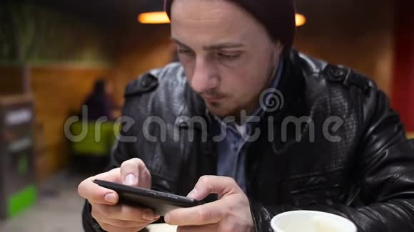 坐在咖啡馆里玩智能手机游戏的年轻人视频的预览图