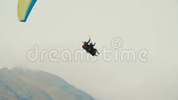 在美丽的群山背景下乘坐滑翔伞飞行的游客视频的预览图