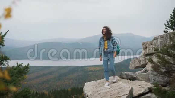女游客在上面是快乐和庆祝成功一个女人穿着牛仔夹克在世界的顶端在一个视频的预览图