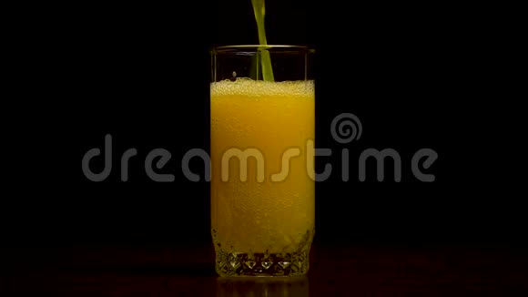 橙色苏打水大玻璃溢出的橙色苏打水特写与气泡隔离在黑色背景橙色汽水视频的预览图