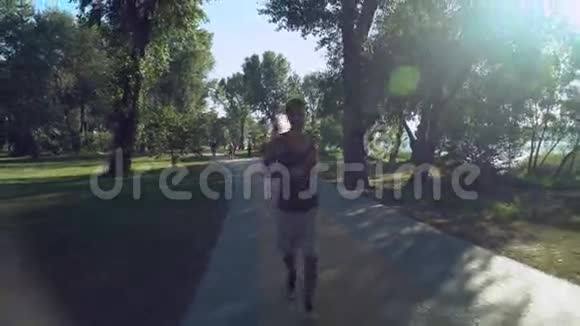 一个带着耳机的年轻人跑回公园在那里散步和跑步其他人视频的预览图