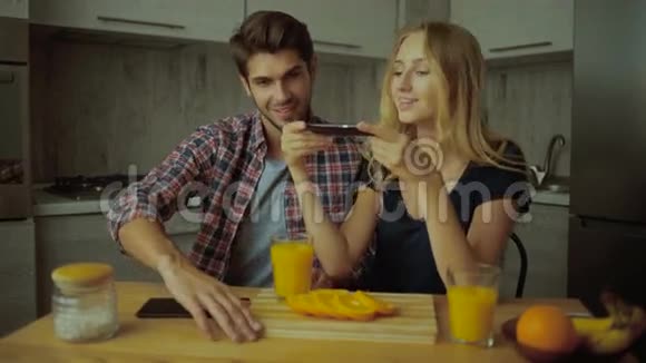 有趣的一对夫妇在厨房里拍美味的橘子视频的预览图
