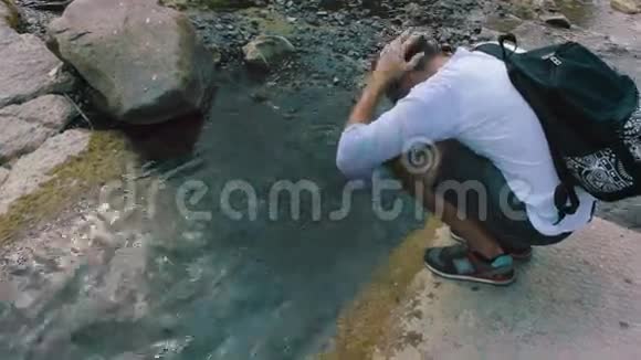 年轻人把头伸进一条干净凉爽的山溪里视频的预览图