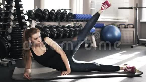 一位漂亮的年轻女子在健身房里练腿视频的预览图