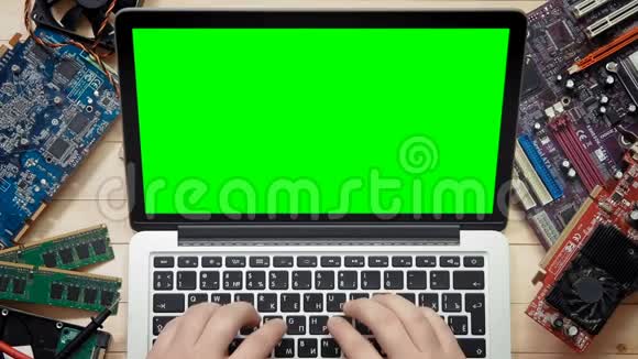 顶视图计算机技术人员使用带有绿色屏幕的笔记本电脑并配有工具和电子部件视频的预览图