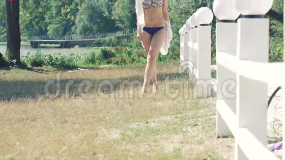 穿泳装的时髦女孩走在海边的绿草上慢慢地视频的预览图