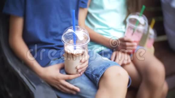 男孩和女孩少年坐在长凳上手里拿着带着新鲜和冰沙的眼镜4k慢动作视频的预览图