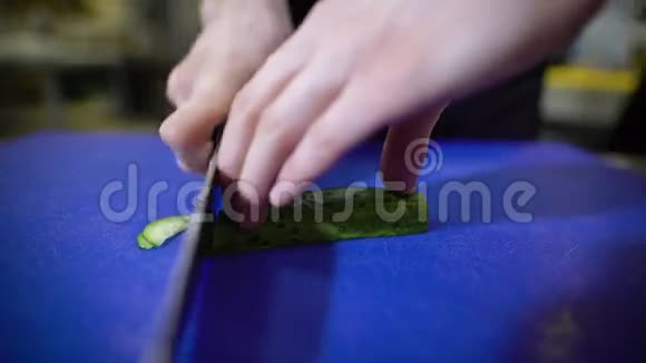 用锋利的刀在蓝色塑料雕刻板上专业切黄瓜餐厅的厨师视频的预览图