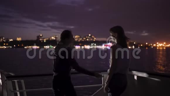 两个迷人的年轻女人在夜晚在船上旅行的剪影船上的女朋友视频的预览图