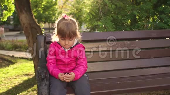 可怜的小孩坐在公园的长凳上视频的预览图
