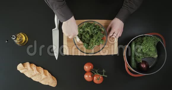 男人正在用一个透明的碗做沙拉其他蔬菜和面包放在附近视频的预览图