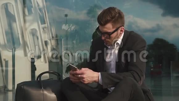 机场的漂亮胡子商人在他的智能手机上输入短信玻璃墙背景视频的预览图