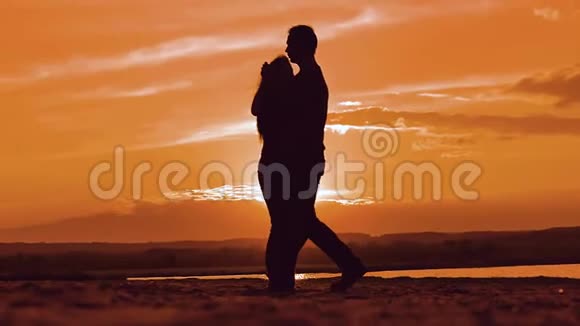 一对幸福的年轻夫妇的剪影男女在日落时分在外面缓慢地跳舞一对享受大自然的夫妇视频的预览图