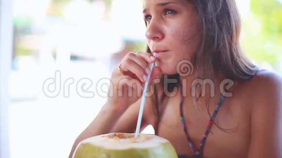 可爱的年轻黑发女人度假喝新鲜椰子水从绿色的年轻椰子水果1920x1080视频的预览图
