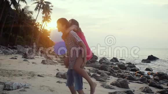 恋爱中的情侣们玩得开心拿着五颜六色的气球旋转在热带海滩度假视频的预览图