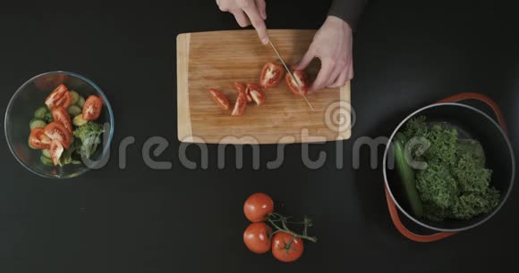 人在其他蔬菜附近的木质砧板上切番茄上景视频的预览图