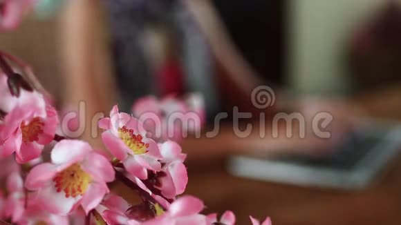 女人坐在办公桌前在笔记本电脑上工作装饰樱花靠近女人视频的预览图