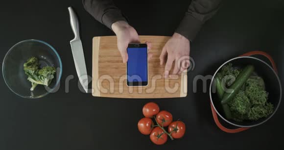 上景手与电话上方的切割板蔬菜和刀放在附近视频的预览图