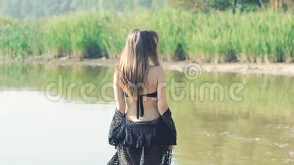 穿泳装的时髦女孩在河上摆姿势慢慢地视频的预览图