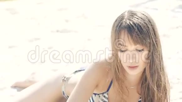 穿泳装的漂亮女人躺在沙滩上撒沙慢慢地视频的预览图
