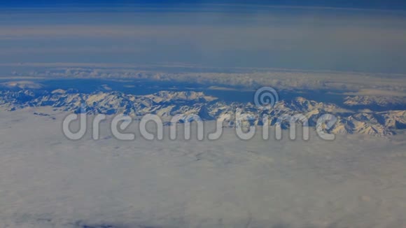 从鸟瞰飞机窗口的地平线和云层和白雪覆盖的山脉视频的预览图