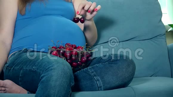 孕妇双手抚摸大肚子膝盖上放着樱桃浆果视频的预览图