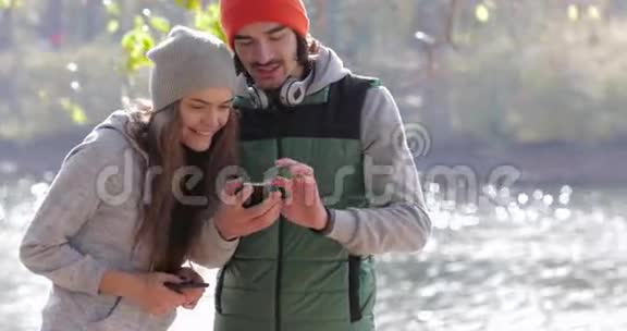 年轻夫妇男人和漂亮女人使用手机户外日出早秋公园视频的预览图
