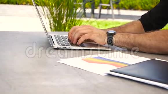 手在笔记本电脑键盘上打字文件在外面的桌子上视频的预览图