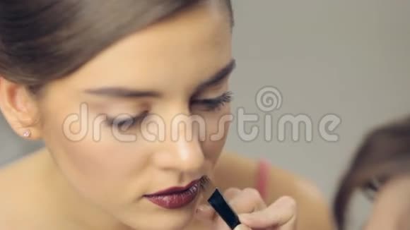 在年轻女人的嘴唇上涂化妆品全景视频的预览图