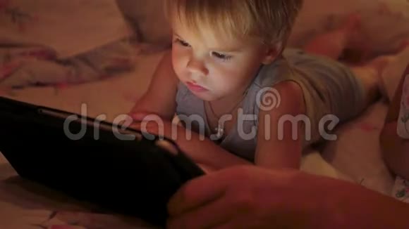 傍晚时分一个小男孩在平板上看动画片视频的预览图