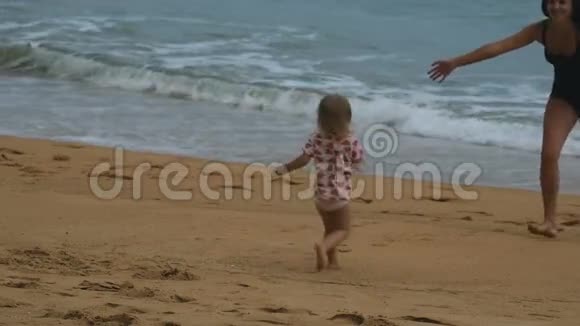 妈妈把小女孩抱在怀里沙滩上视频的预览图