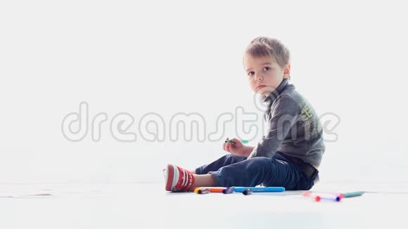 一个男孩坐在白色的地板上画画视频的预览图