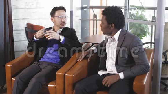 欧洲男人和非裔美国人坐在扶手椅上谈判视频的预览图