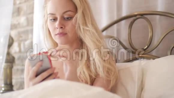 在床上使用手机的女孩手指做手势触摸打字文本滑动和滚动屏幕视频的预览图