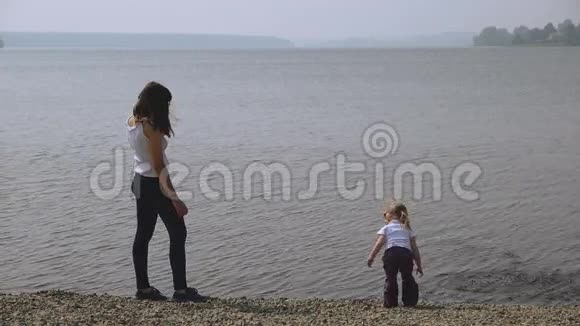 母亲和女儿把石头扔进池塘视频的预览图